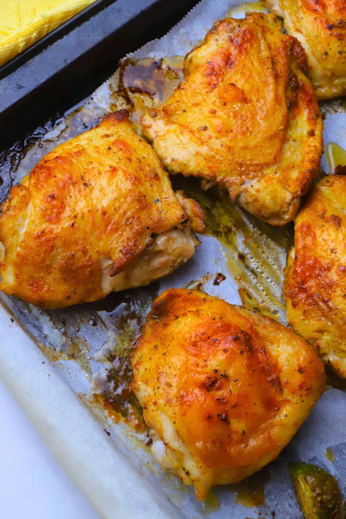 Low carb baked chicken thighs on a parchment lined sheet pan.