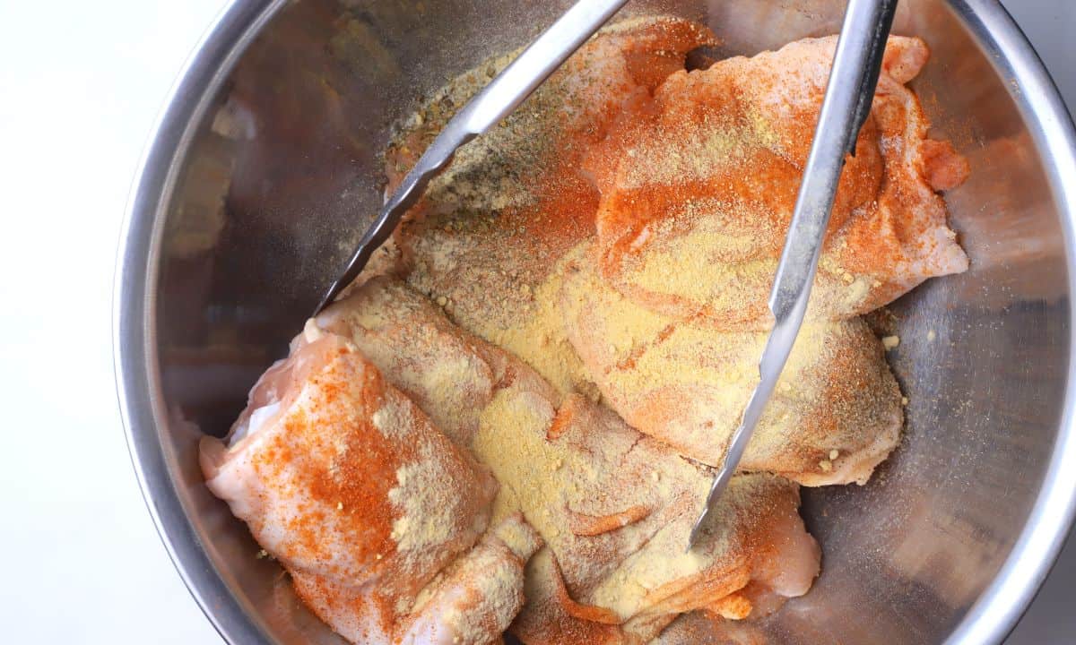 Seasoning the chicken in a bowl.