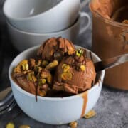 Dubai chocolate pistachio ice cream in a bowl next to the ninja creami pint with more ice cream.