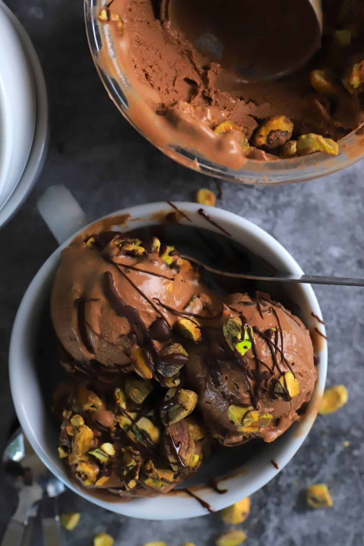 Dubai chocolate pistachio ice cream in a bowl next to the ninja creami pint with more ice cream.