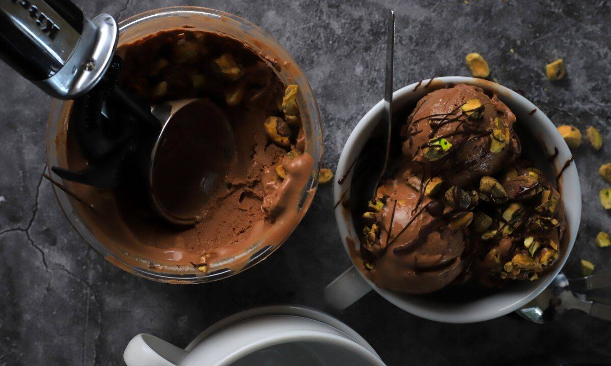 Dubai chocolate pistachio ice cream in a bowl next to the ninja creami pint with more ice cream.