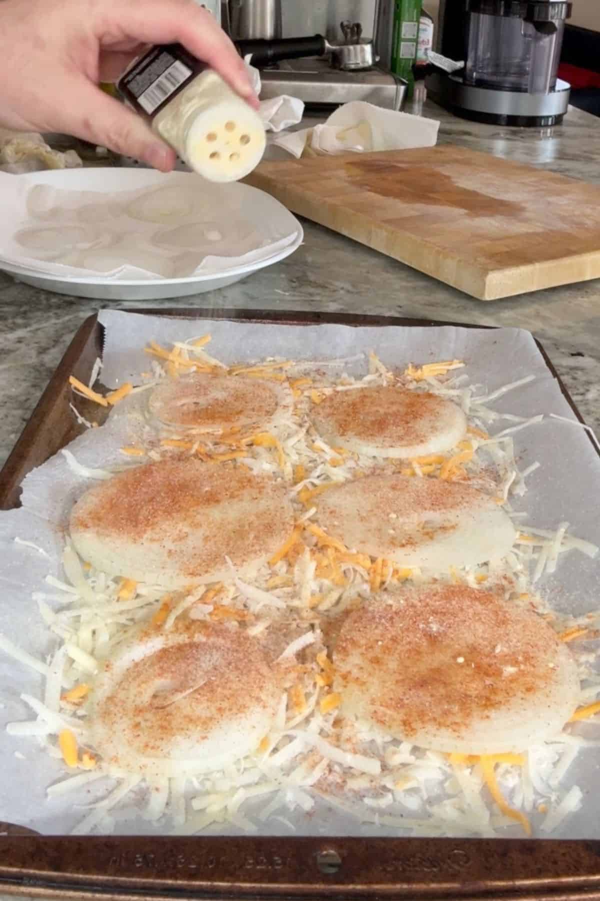 Sliced onions on a parchment lined sheet pan.